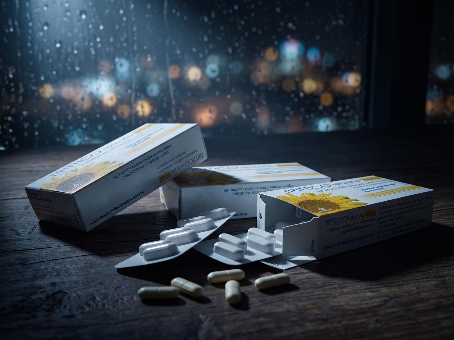 Tri krabičky lieku Trittico položené na tmavom stole v nočnom šere, symbolizujúce záchrannú brzdu vyčerpaného nervového systému.
